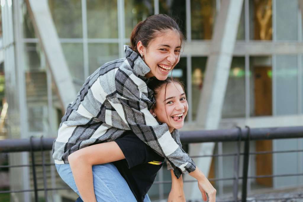 Two people smiling outdoors, one giving the other a piggyback ride